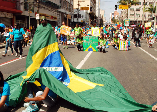Sob a bandeira, crianças se protegem do sol, na avenida Francisco Glicério, em Campinas (foto: João Zinclar)